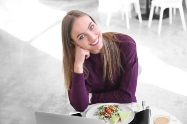 Young woman at table in cafe clipart