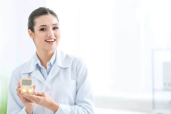 Kvindelig læge holder kontaktlinse sag indendørs - Stock-foto