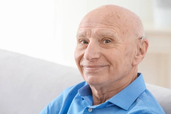 Äldre man med hörapparat inomhus — Stockfoto
