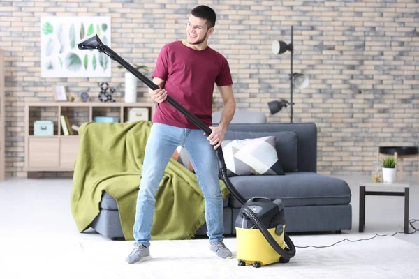 Jonge man hoovering vloer tijdens het schoonmaken van plat — Stockfoto