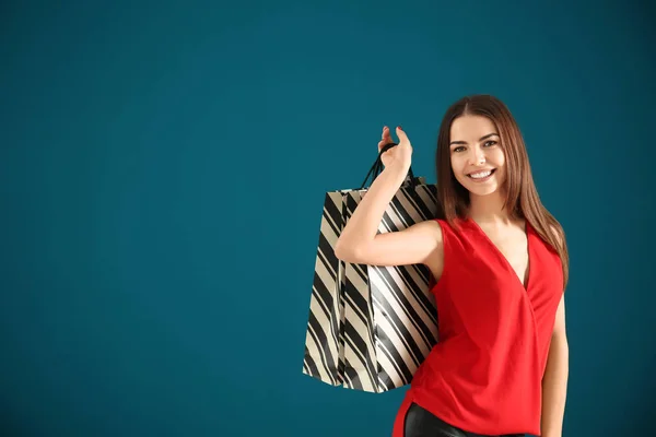 Giovane donna con borse della spesa su sfondo colore — Foto Stock