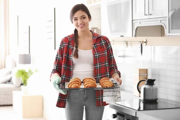 Žena držící tác s croissanty v kuchyni. Čerstvý z trouby — Stock fotografie