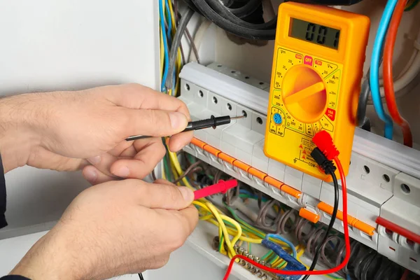 年轻电工测量配电板电压 — 图库照片