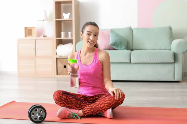 Hermosa joven con botella de agua después de hacer ejercicios de fitness en casa — Foto de Stock