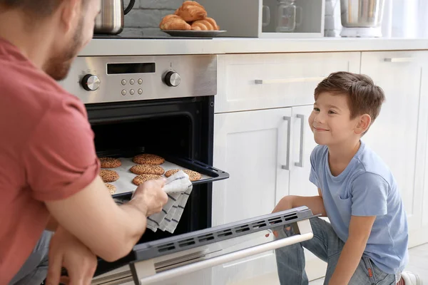 Kisfiú néz ő Atya sütni cookie-kat, a beltéri sütő — Stock Fotó