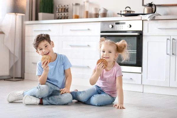 Anak-anak kecil makan kue lezat dekat oven di dapur — Stok Foto