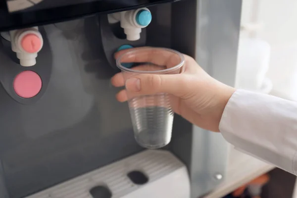 Vrouw vullen plastic beker van waterkoeler, close-up — Stockfoto