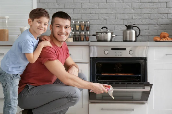 Kleiner Junge beobachtet Vater beim Plätzchenbacken im Backofen — Stockfoto