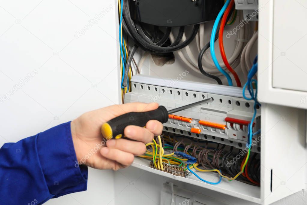 Young electrician repairing distribution board, closeup