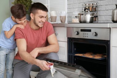 Küçük çocuk babası bake çerezleri fırın kapalı izlerken