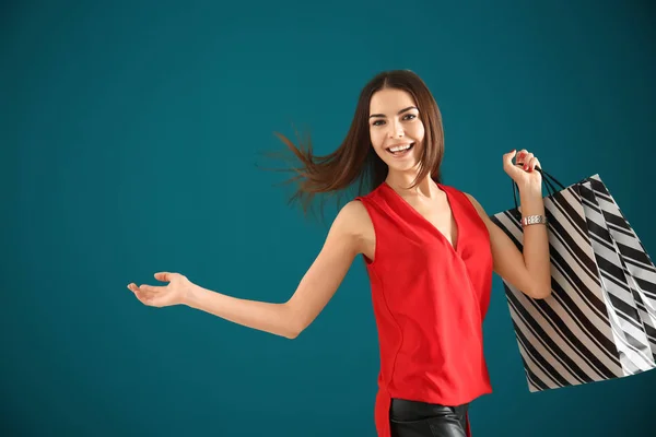 Mujer joven con bolsas de compras en el fondo de color —  Fotos de Stock