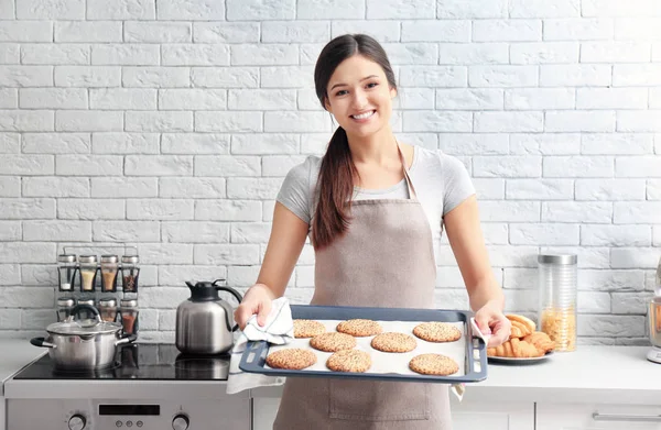 Žena držící tác s cookies v kuchyni. Čerstvý z trouby — Stock fotografie