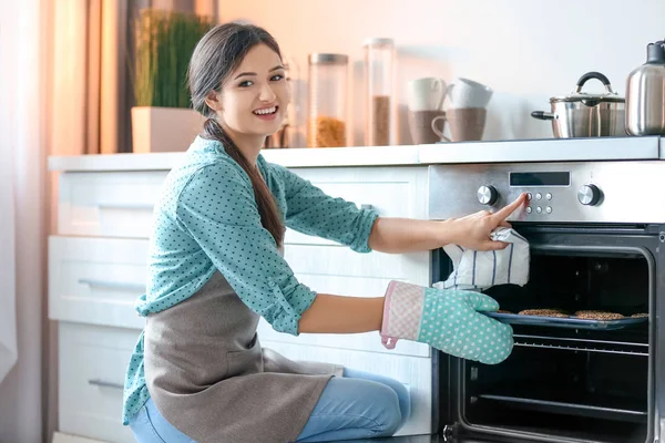 Жінка випікає печиво в духовці в приміщенні — стокове фото