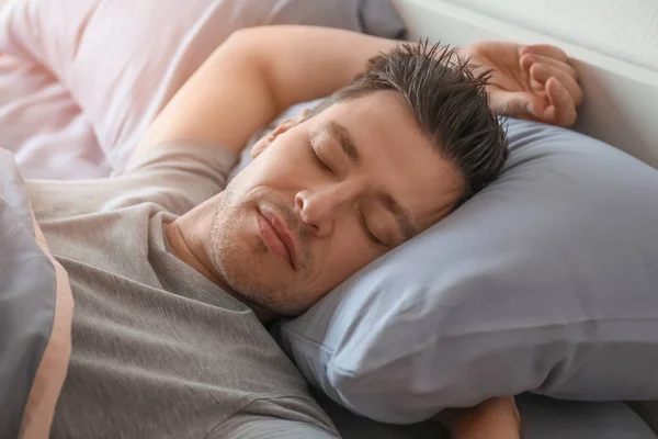 Молодой человек спит в постели дома — стоковое фото