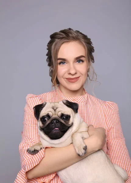 Jovem com cachorro bonito no fundo cinza. Adoção de animais — Fotografia de Stock