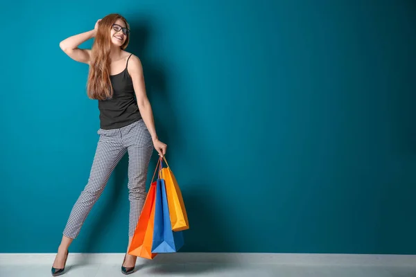 Mulher bonita com sacos de compras contra parede de cor — Fotografia de Stock