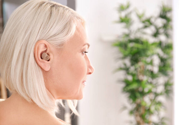 Зрелая женщина со слуховым аппаратом в помещении
