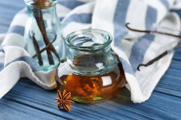 Glass jar with vanilla extract on wooden table
