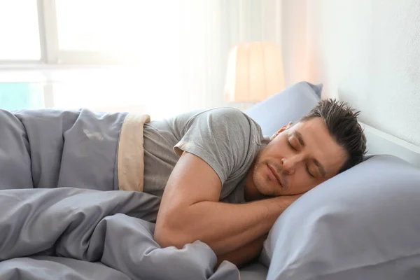 Молодой человек спит в постели дома — стоковое фото