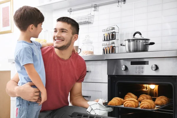 Kisfiú néz ő Atya sütni croissant, bent a sütőben — Stock Fotó