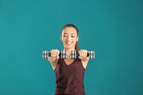 Mooie jonge vrouw doen fitness oefening met halters op kleur achtergrond — Stockfoto