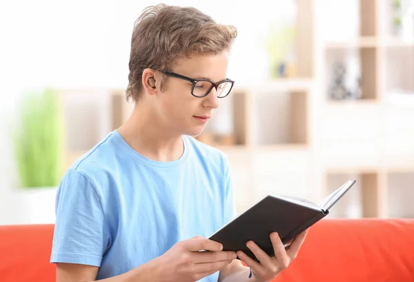 Adolescente com aparelho auditivo leitura livro dentro de casa — Fotografia de Stock