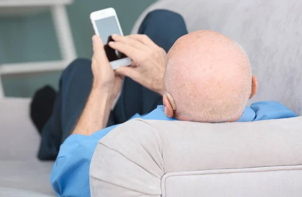 スマート フォンを用いた屋内での補聴器と年配の男性 — ストック写真