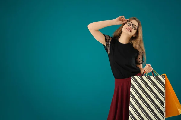 Beautiful young woman with shopping bags on color background — Stock Photo, Image