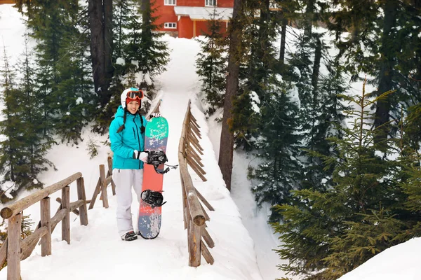 Joyeux snowboarder féminin sur le pont de la station enneigée. Vacances d'hiver — Photo