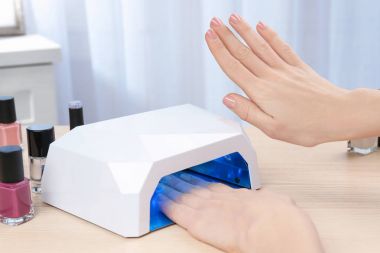 Masada manikür için UV lamba kullanan kadın