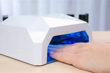 Masada manikür için UV lamba kullanan kadın