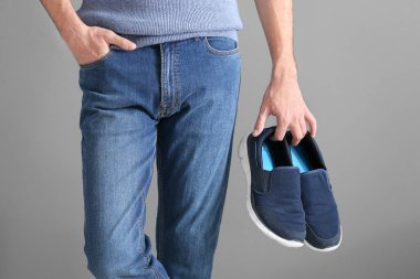 Ayakkabı gri arka plan üzerinde tutan adam