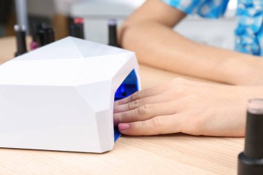 Masada manikür için UV lamba kullanan kadın