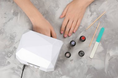 Masada manikür için UV lamba kullanan kadın