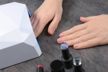 Masada manikür için UV lamba kullanan kadın