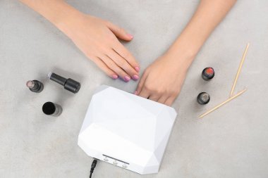 Masada manikür için UV lamba kullanan kadın