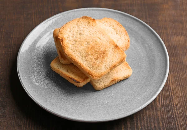 Plaat met lekker geroosterd brood op tafel — Stockfoto