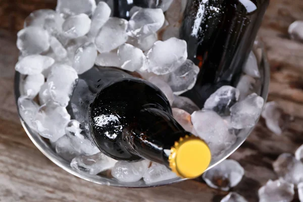 Bowl with bottles of beer in ice on wooden background, closeup — Stock Photo, Image