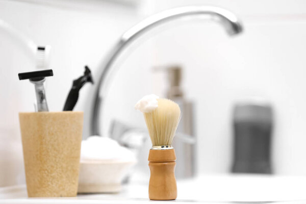Shaving brush with foam and razors for man on sink