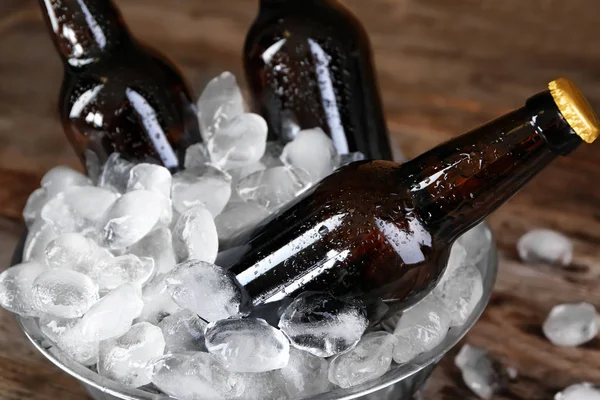 Cuenco con botellas de cerveza en hielo sobre fondo de madera, primer plano —  Fotos de Stock