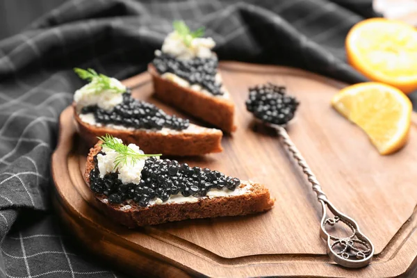 Sandwiches with delicious black caviar and cottage cheese on wooden board — Stock Photo, Image