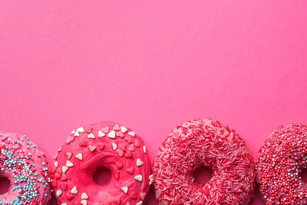 Deliziose ciambelle rosa su sfondo di colore — Foto Stock