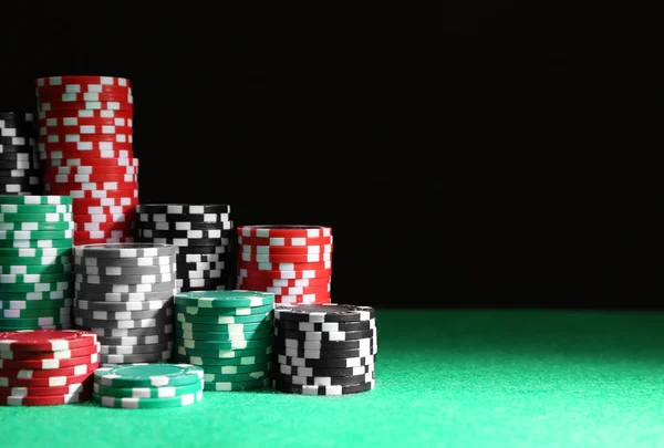 Chips Casino sul tavolo verde contro sfondo nero — Foto Stock