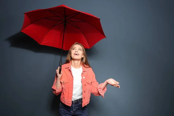 Giovane donna con ombrello rosso su sfondo a colori — Foto Stock