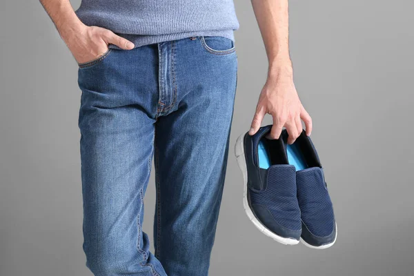 Hombre sosteniendo zapatos sobre fondo gris —  Fotos de Stock