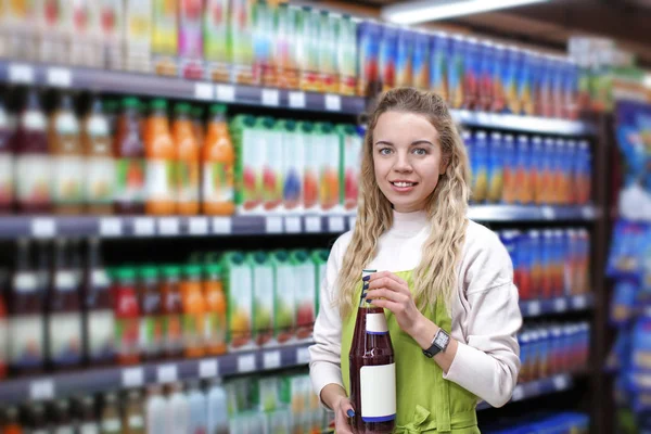 Νεαρή γυναίκα με το μπουκάλι του χυμού στο κατάστημα. Ιδιοκτήτης μικρής επιχείρησης — Φωτογραφία Αρχείου