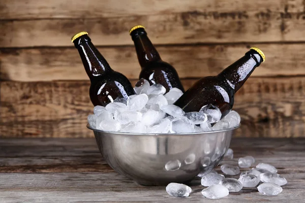 Bowl with bottles of beer in ice on wooden background — Stock Photo, Image