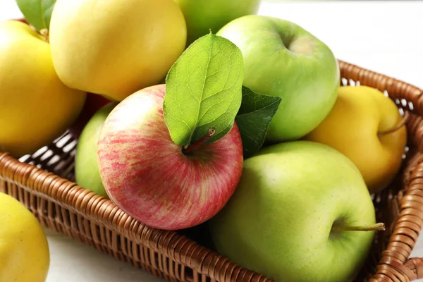 Juicy apples in basket on wooden table, closeup — Stock Photo, Image