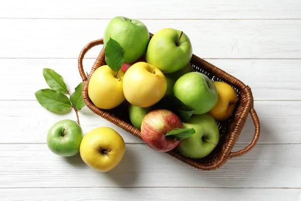 Sappige appels in de mand op houten tafel, bovenaanzicht — Stockfoto