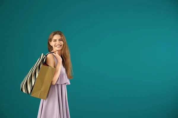 Mulher bonita com sacos de compras no fundo de cor — Fotografia de Stock